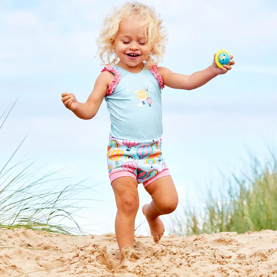 Mädchen läuft am Strand und trägt den Badeanzug