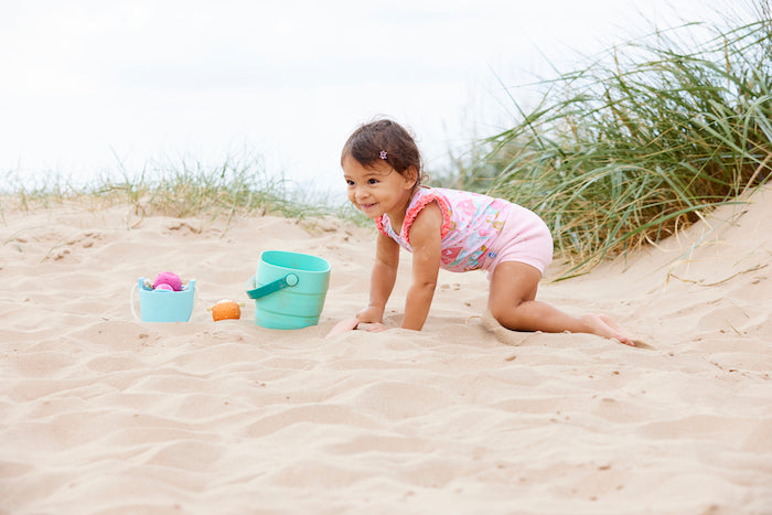 Mädchen spielt am Strand und trägt den  Badeanzug "Owl and the Cat" mit Sonnenschutzfaktor 50+