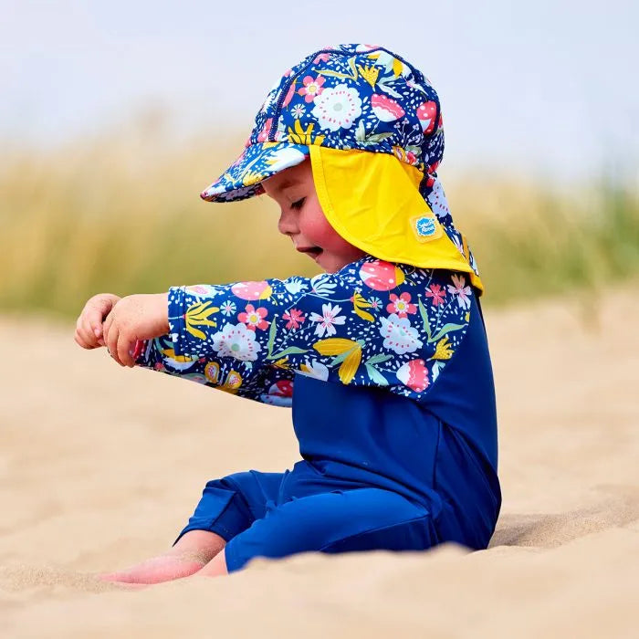 Mädchen am Strand trägt UV Schutzkleidung aus Sonnenhut und Schwimmanzug "Garden Delight"