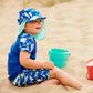 Junge spielt am Strand und trägt den UV Sonnenhut "Up in the Air"