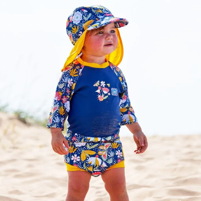 Mädchen am Strand trägt UV Sonnenhut und UV Schwimmanzug "Garden Delight"