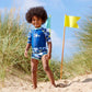 Junge am Strand trägt Sonnenschutzkleidung "Up in the Air"