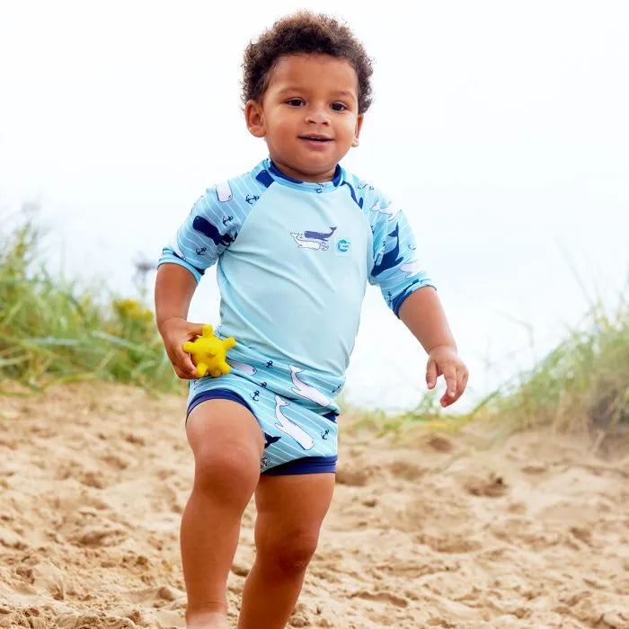 Junge am Strand spielt in der Sonne mit dem UV Schwimmanzug "Vintage Moby"