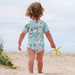 Mädchen am Strand trägt den Wetsuit "Little Ducks" mit Sonnenschutzfaktor 50+