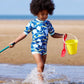 Junge am Strand trägt den Wetsuit "Up in the Air" mit Sonnenschutzfaktor 50+