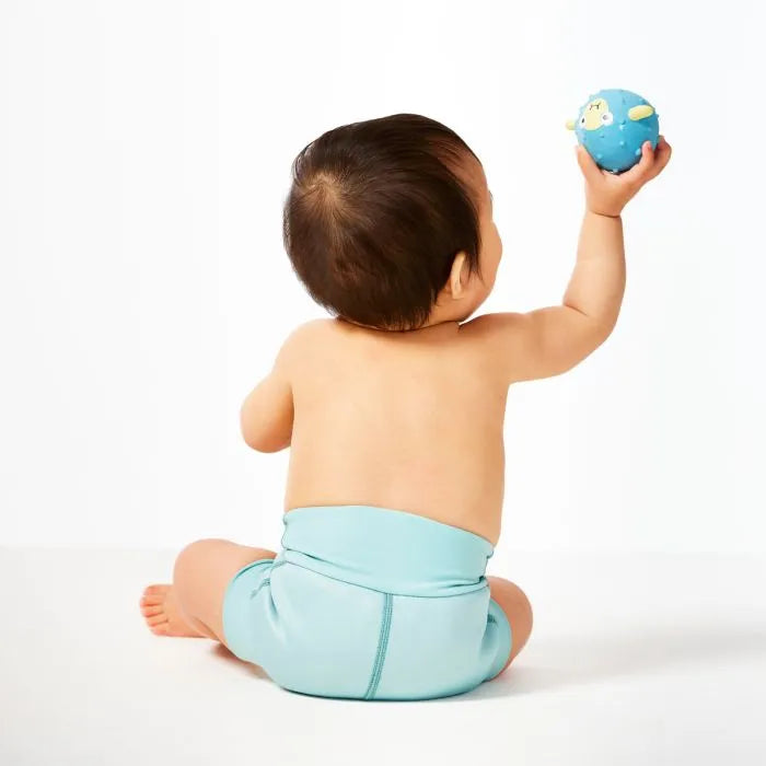 Kind trägt bequeme Schwimmwindel "Pistachio" und spielt mit einem Ball