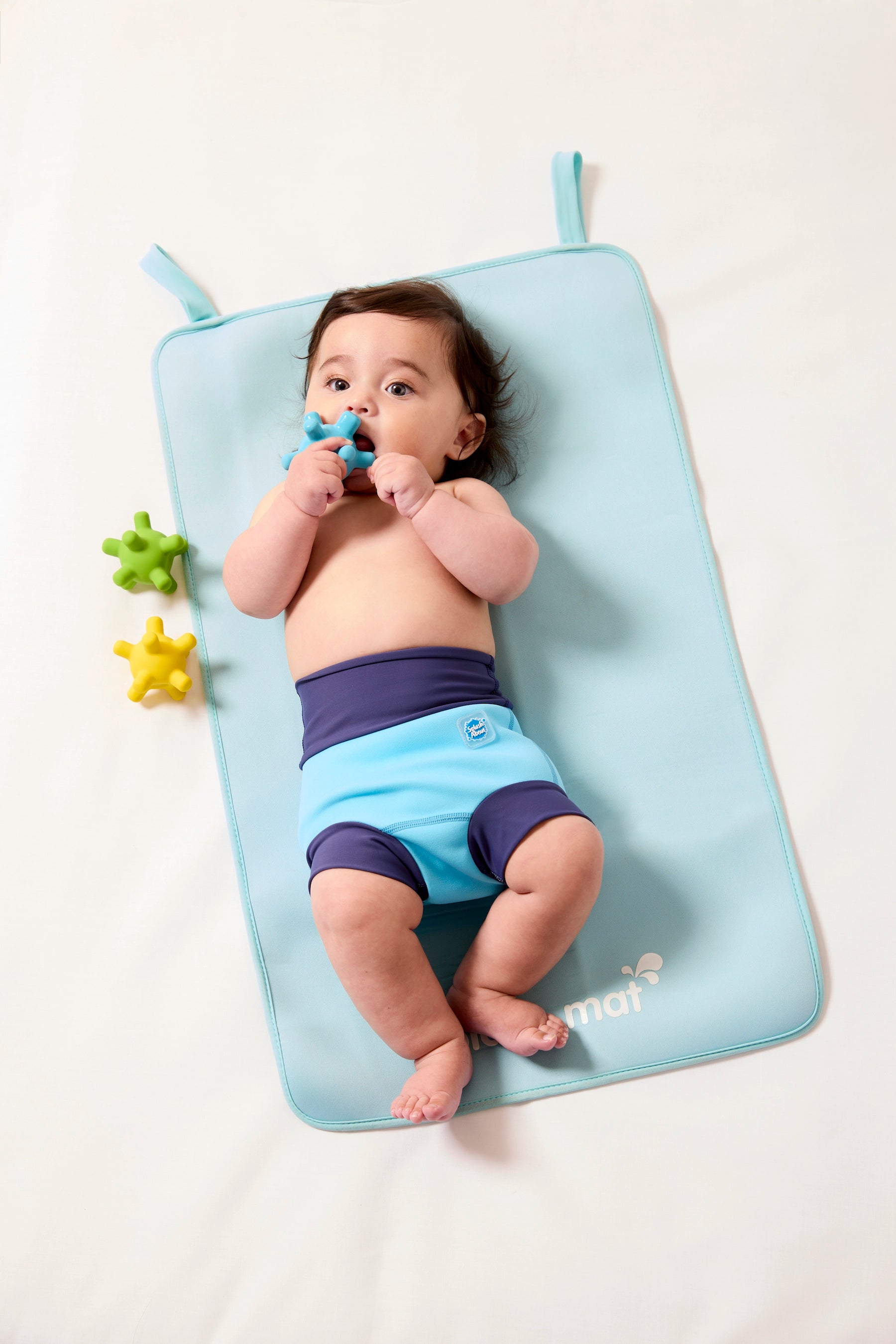 Kind trägt Schwimmwindel "Blue Cobalt" und liegt auf antibakterieller Wickelunterlage
