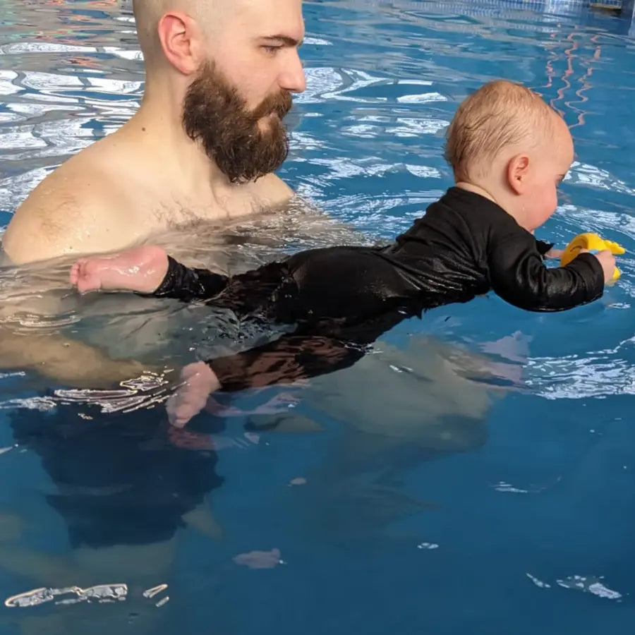 Baby trägt den Neoprenanzug im Wasser